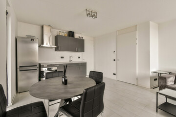 a kitchen and dining area in a modern style apartment with white walls, black chairs and an open...