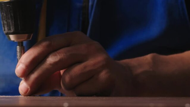 Close-up of worker drilling nails with drill. Creative. Man screws nails with drill. Drilling with drill during crafting work