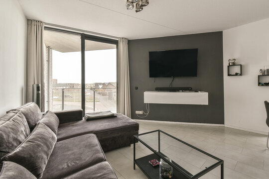 a living room with grey couches and a flat screen tv mounted on the wall in the corner of the room