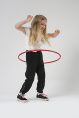Studio portrait of beautiful cheerful little girl playing with red hula hoop © triocean