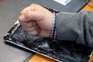 A man's fist smashes an electronic tablet.