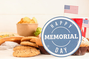 Card with text HAPPY MEMORIAL DAY, cookies, muffins and potato chips on light table, closeup