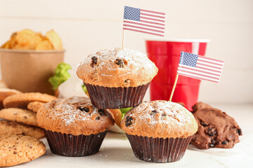 Tasty muffins, cookies, potato chips and cup of drink on light table, closeup. Memorial Day celebration