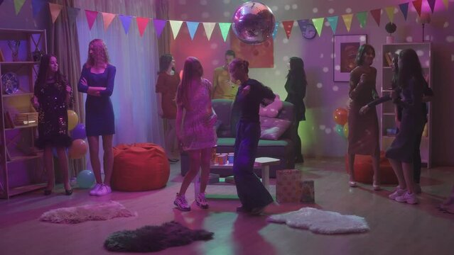 A company of teenagers dance incendiary at a house party, except for one informal girl. The girl keeps aloof feeling awkward and uncomfortable. HDR BT2020 HLG Material.