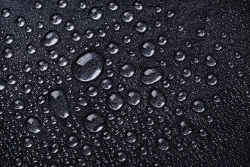 Water drops on black background top view. Black raindrops, abstract background.