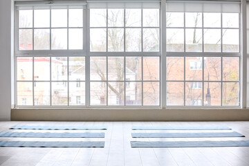 Fototapeta na wymiar Yoga mats on floor near window in gym