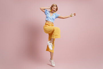 Full length of fashionable young woman dancing and smiling against color background