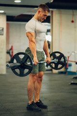 Full length of a strong sportsman lifting a barbell in a gym.