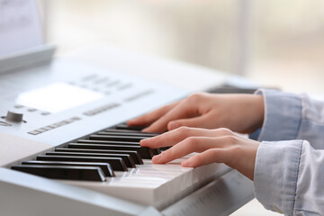 Obraz na płótnie Canvas Little girl playing synthesizer at home, closeup