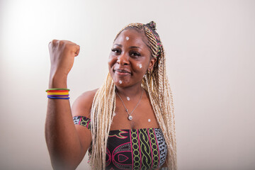 An African lesbian girl with her arm raised shows her biceps and wears a rainbow bracelet