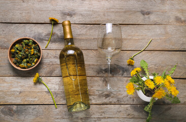 Bottle and glass of dandelion wine on wooden background