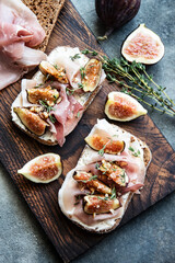 Breakfast with figs, cream cheese and  ham  toasts on a wooden board