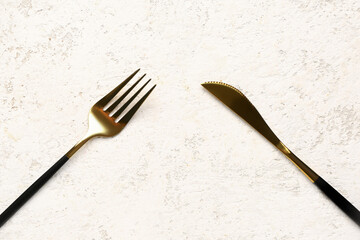 Golden fork and knife with black handles on white background
