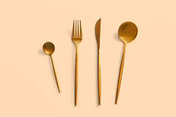 Golden cutlery on beige background