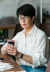 Smiling mature woman holds makeup brushes - cosmetic product concept
