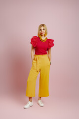 Full length of fashionable young woman standing against colored background