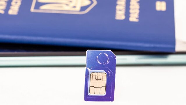 Sim card on the background of a mobile phone and a passport of Ukraine