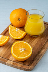 Fresh orange juice in a glass and whole oranges on a wooden chopping board. The concept of healthy eating.
