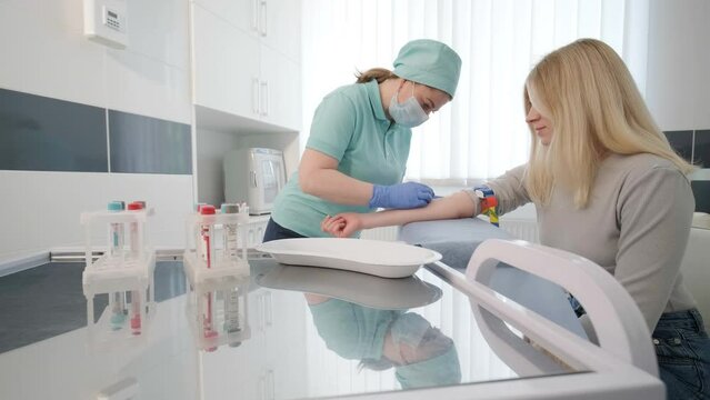 A doctor in a hospital gently draws blood from a girl for diagnostic tests.