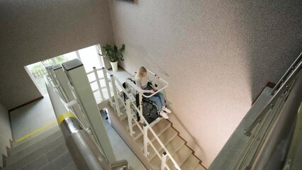 A girl in a wheelchair effortlessly ascends the stairs using a stair lift.
