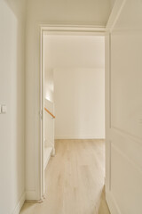 an empty room with white walls and wood flooring on either side of the room, there is a door leading to another room