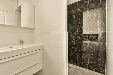 a bathroom with black and white marble tiles on the walls, along with a large mirror in the shower...