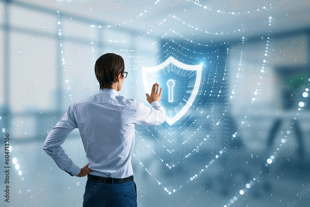 Poster Back view of businessman using glowing polygonal web security shield hologram on blurry office interior background. Digital interface and protection concept. Double exposure.