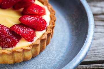 Strawberry tart, popular French pastry or Italian. Served on a plate placed on a rustic wooden table. Seasonal dessert. 