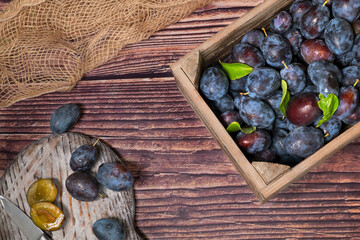 A wooden box with freshly harvested plums are processed