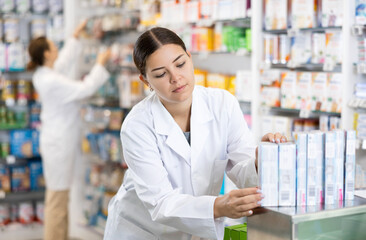 Pharmacy employee puts new healing body cosmetics on the shelves