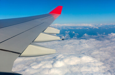 View from the window on the wing of the plane and passing snow-white clouds.