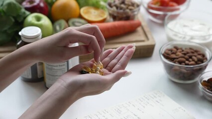Woman Asian Professional Nutritionist checking dietary supplements in hand, surrounded by a variety of fruits, nuts, vegetables, and dietary supplements on the table