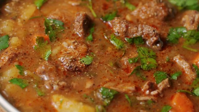 Hungarian goulash soup cooking close-up in pot, chef cook traditional polish or zech soup in restaurant. 