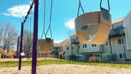 Empty Swing in Playground, Kidnapping Concept. Empty Playground in the Park With Swings on a Sunny Day With Canadian Houses.
