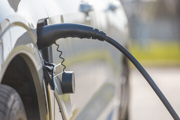 Charging an electric car with a connected power cable close-up.  The concept of ecological...