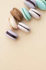 Different pastel colors pastry macarons top view on a beige background with copy space