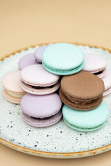 Different pastel colors pastry macaroons on a beige background