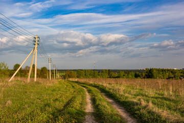 Scenic landscape in the countryside with a country road and a power line with wires