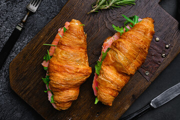 Croissant with salmon and cream cheese, on black dark stone table background, top view flat lay