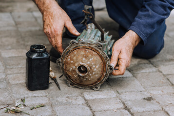 Male professional worker, electrician, electromechanic repairing an old rusty electric motor in a...