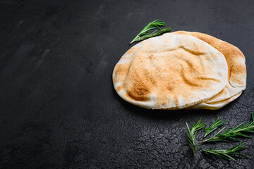 Pita flat bread set, on black dark stone table background, with copy space for text