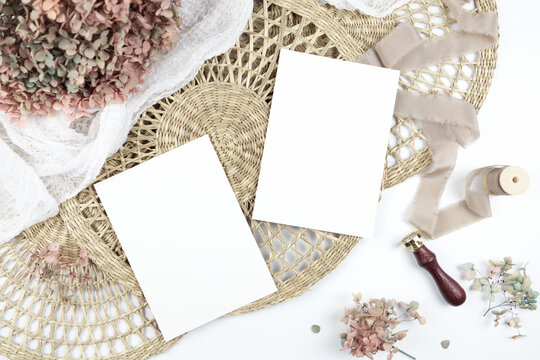 Double sided 5x7 invitation greeting card, envelope. Wedding stationery suite mock-up styled with boho decor, dried hydrangea flowers bouquet, rattan lace mats, vintage wax seal, and silk ribbon.