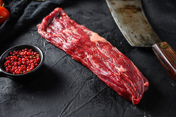 Raw machete also known as bistro steak, fajita meat or onglet, near butcher knife with pink pepper...