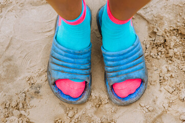 A woman in blue sandals stands on the beach on the sand. Photography, portrait.