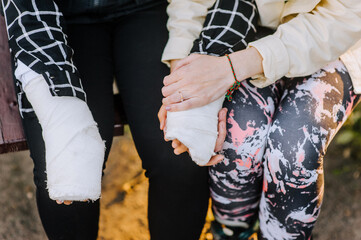 A caring woman, mother, girlfriend holds hands in a cast, bandage a girl, a child after a bone fracture, takes care, reassuring. Close-up photography, portrait, rehabilitation.