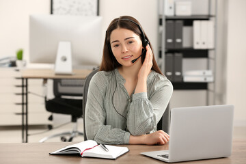 Hotline operator with headset working on laptop in office