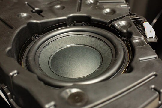 Subwoofer speaker in a plastic case for mounting in the trunk in the spare wheel, a close-up of the car's speaker system.