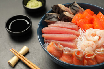 Delicious mackerel, salmon, shrimps and tuna served with funchosa, soy sauce and wasabi on grey table, closeup. Tasty sashimi dish