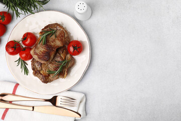 Delicious fried meat with rosemary and tomatoes served on light grey table, flat lay. Space for text