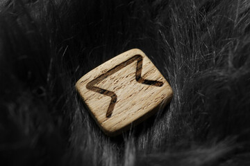 Wooden rune Perth on grey faux fur, closeup